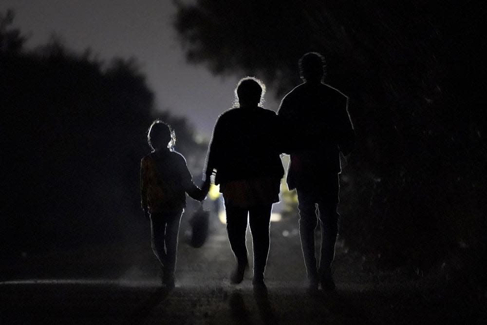 In this March 21, 2021, file photo a 7-year-old migrant girl from Honduras, left, walks with Fernanda Solis, 25, center, also of Honduras, and an unidentified man as they approach a U.S. Customs and Border Protection processing center to turn themselves in while seeking asylum moments after crossing the U.S.-Mexico border in Mission, Texas. (AP Photo/Julio Cortez)