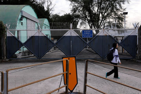 A student walks past a gate of Osborn Barracks, also know as Kowloon East Barracks used by the Chinese People's Liberation Army in Hong Kong's Kowloon Tong, China December 1, 2017. REUTERS/Tyrone Siu/Files