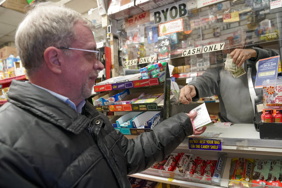 A customer buys a chance at the $940 million Mega Millions Lottery jackpot at a convenience store on the Upper East Side of Manhattan, Friday, Jan. 6, 2023 in New York. (AP Photo/Mary Altaffer)