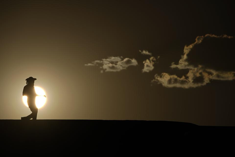 FILE - A person walks along a trail as the sun sets, July 16, 2023, in Death Valley National Park, Calif. More Americans believe they've personally felt the impact of climate change because of recent extreme weather, including a summer that brought dangerous heat for much of the United States, according to new polling from The Associated Press-NORC Center for Public Affairs Research. (AP Photo/John Locher, File)