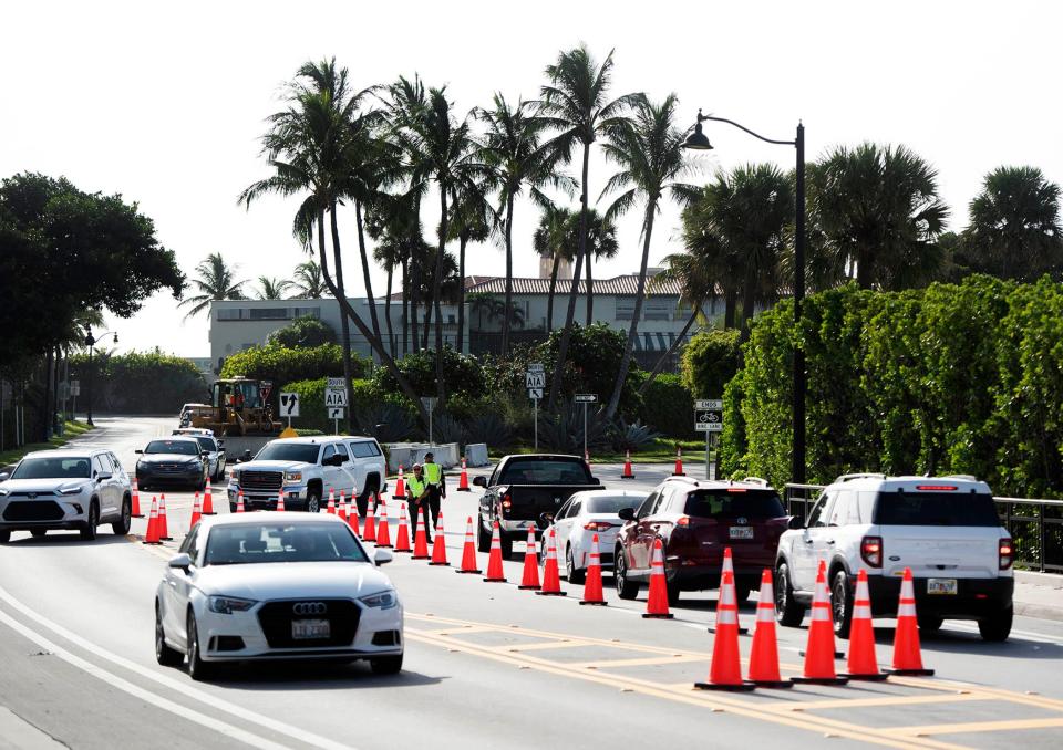 Florida Department of Transportation workers use a bulldozer to place concrete barriers near the roundabout at the east end of Southern Boulevard as Palm Beach County Sheriff's Office deputies direct traffic on Southern Boulevard Saturday morning.  Palm Beach announced this week that the Secret Service would close South Ocean Boulevard near former President Donald Trump's Mar-a-Lago Club, starting Saturday morning and lasting at least until the Nov. 5 general election.