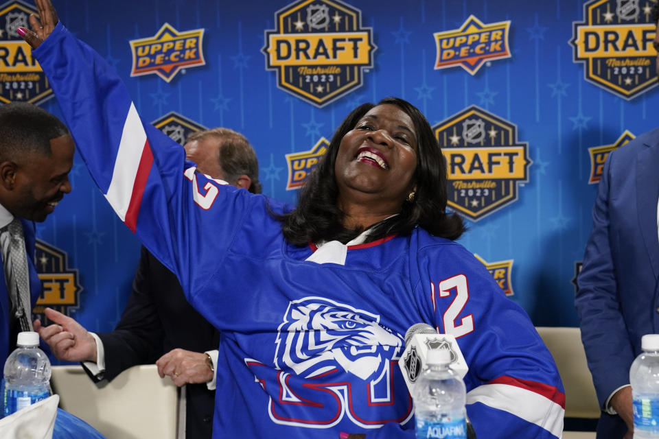 Tennessee State University President Glenda Glover puts on a hockey jersey during a news conference, Wednesday, June 28, 2023, in Nashville, Tenn. The university announced its plans to become the first historically Black college and university to introduce ice hockey. (AP Photo/George Walker IV)