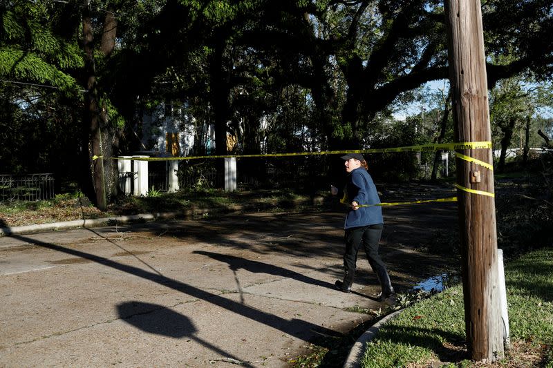 A police officer puts police caution tape in a street blocked by a tree that was blown down after Hurricane Delta, in Jennings