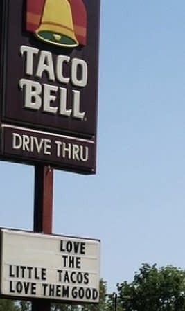 sign reading love the little tacos love them good below a Taco Bell sign