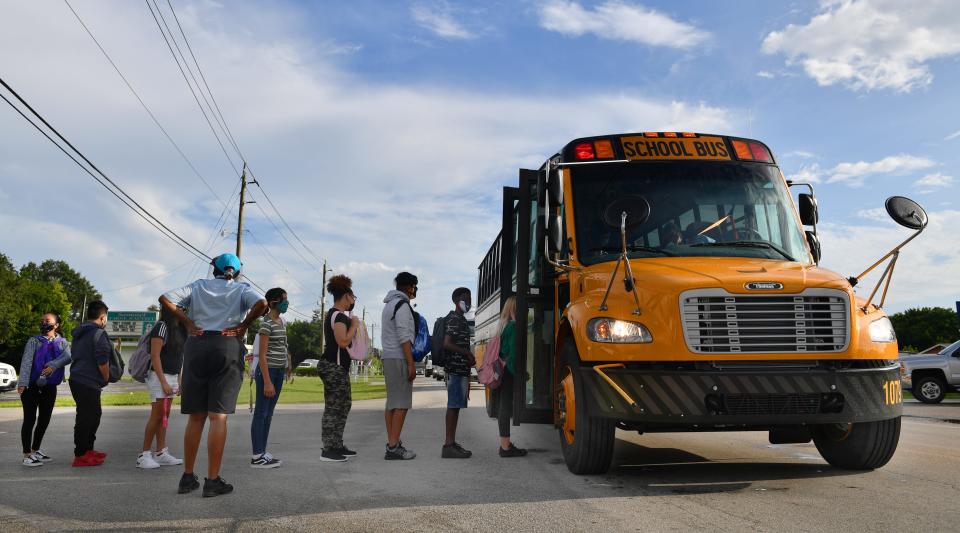 A district employee checks to make sure Martha B. King Middle School students have masks on before boarding their school bus on the first day of classes in Manatee County.