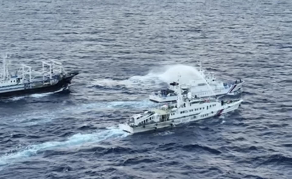 In this image from video handout provided by the Philippine Coast Guard, a Chinese Coast Guard ship, bottom, uses water cannon Philippine coast guard patrol ship, BRP Cabra, center, as it approaches Second Thomas Shoal, locally known as Ayungin Shoal, in the disputed South China Sea on Sunday Dec. 10, 2023. The Chinese coast guard targeted Philippine vessels with water cannon blasts Sunday and rammed one of them, causing damage and endangering Filipino crew members off a disputed shoal in the South China Sea, just a day after similar hostilities at another contested shoal, Philippine officials said. (Philippine Coast Guard via AP)