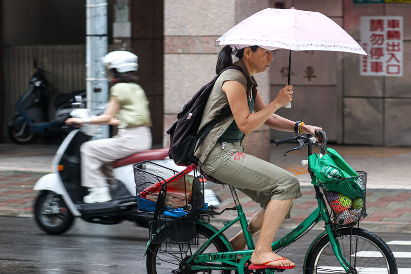 氣象署表示，受到鋒面影響，各地陰雨，30日深夜至5月1日，西半部防大雨，其他各地也都有局部雷陣雨。圖為台北市民眾撐傘騎自行車。（中央社）