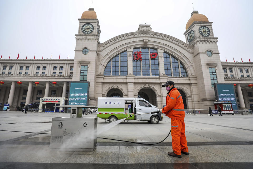 A worker hoses down garbage bins outside the closed Hankou Railway Station in Wuhan in central China's Hubei Province, Thursday, Jan. 23, 2020. Overnight, Wuhan authorities announced that the airport and train stations would be closed, and all public transportation suspended by 10 a.m. Friday. Unless they had a special reason, the government said, residents should not leave Wuhan, the sprawling central Chinese city of 11 million that's the epicenter of an epidemic that has infected nearly 600 people. (Chinatopix via AP)