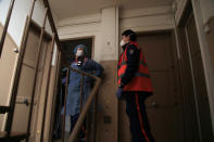 In this photo taken Saturday March 28, 2020, members of the Civil Protection service, Cyril Lamriben, left, and Pierre Leroux wait outside an apartment before checking a woman possibly infected with the Covid-19 virus in Paris. They don't have to put themselves in harm's way, but the volunteers of France's well-known Civil Protection service choose the front line in the fight against the coronavirus. (AP Photo/Michel Euler)