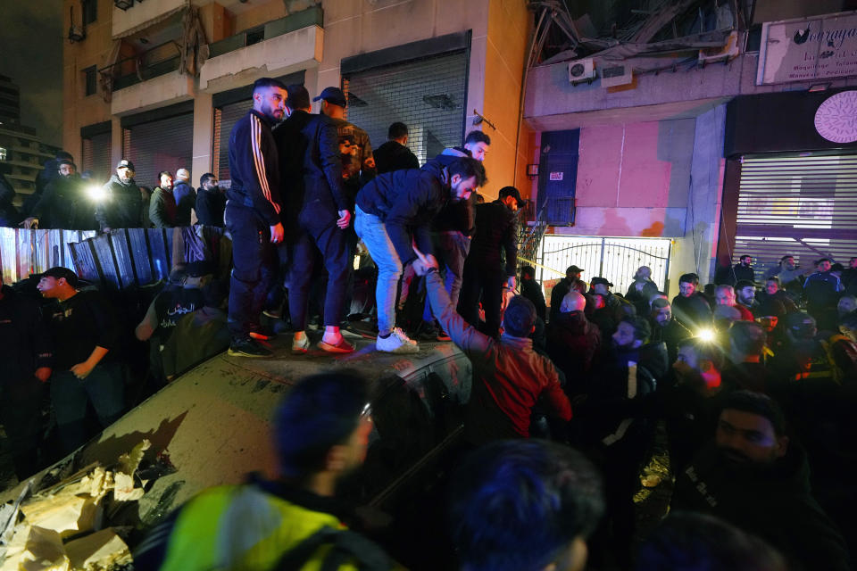 People gather outside a damaged building following a massive explosion in the southern Beirut suburb of Dahiyeh, Lebanon, Tuesday, Jan. 2, 2024. The TV station of Lebanon's Hezbollah group says top Hamas official Saleh Arouri was killed Tuesday in an explosion in a southern Beirut suburb. (AP Photo/Bilal Hussein)