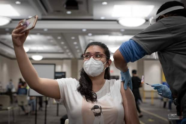 Maria Rey, 27, gets her first does of the Pfizer-BioNTech COVID-19 vaccine at an overnight clinic in Mississauga on May 16, 2021. (Evan Mitsui/CBC - image credit)