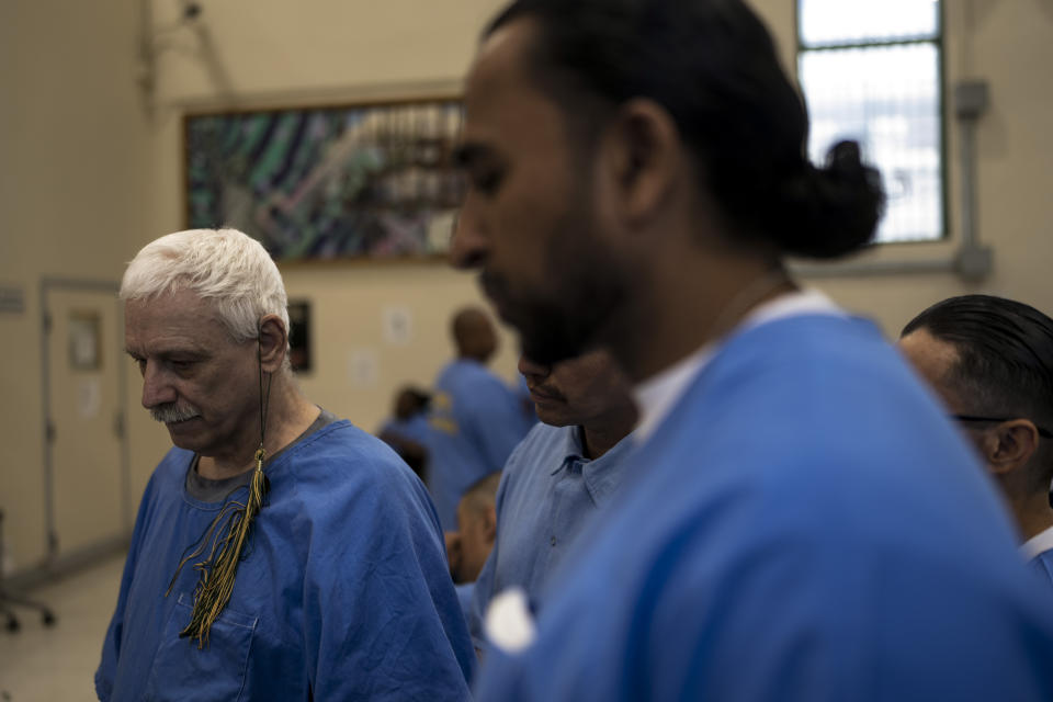 Prisoner-students Leroy Dehaven, left, with a tassel hanging from his ear, and Gerald Massey, foreground, wait to return to their cells after their graduation ceremony at Folsom State Prison in Folsom, Calif., Thursday, May 25, 2023. (AP Photo/Jae C. Hong)
