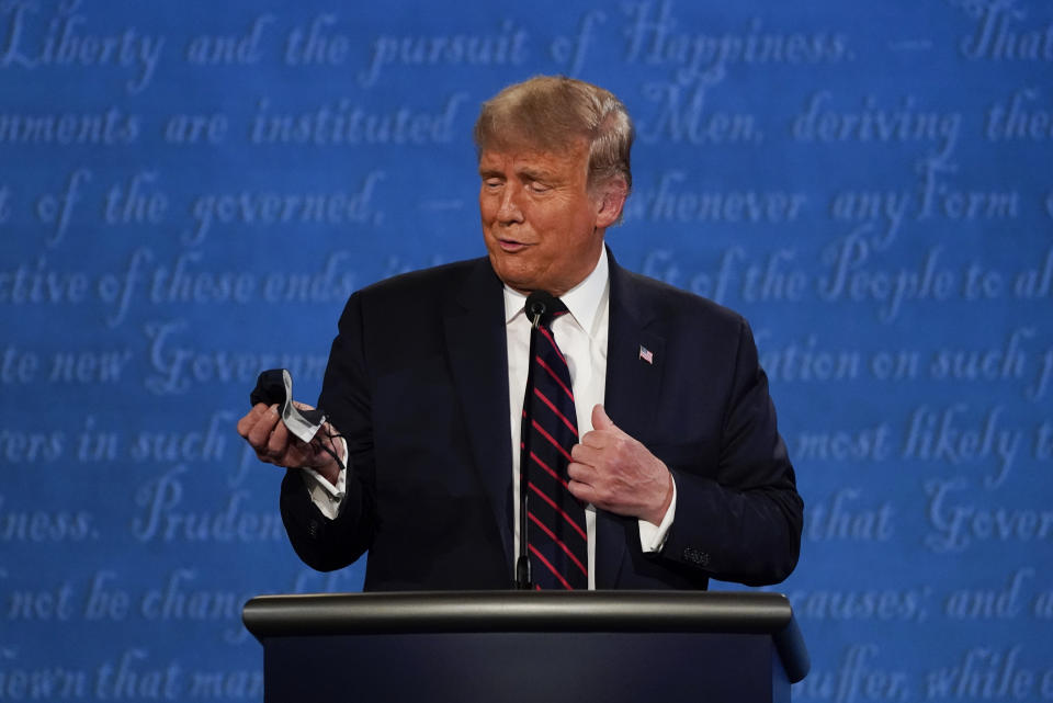 FILE In this Sept. 29, 2020, photo, President Donald Trump looks at his face mask during the first presidential debate at Case Western University and Cleveland Clinic, in Cleveland, Ohio. A book by Donald Trump's ex-chief of staff says Trump tested positive for COVID-19 three days before his first debate in September 2020. (AP Photo/Julio Cortez, File)