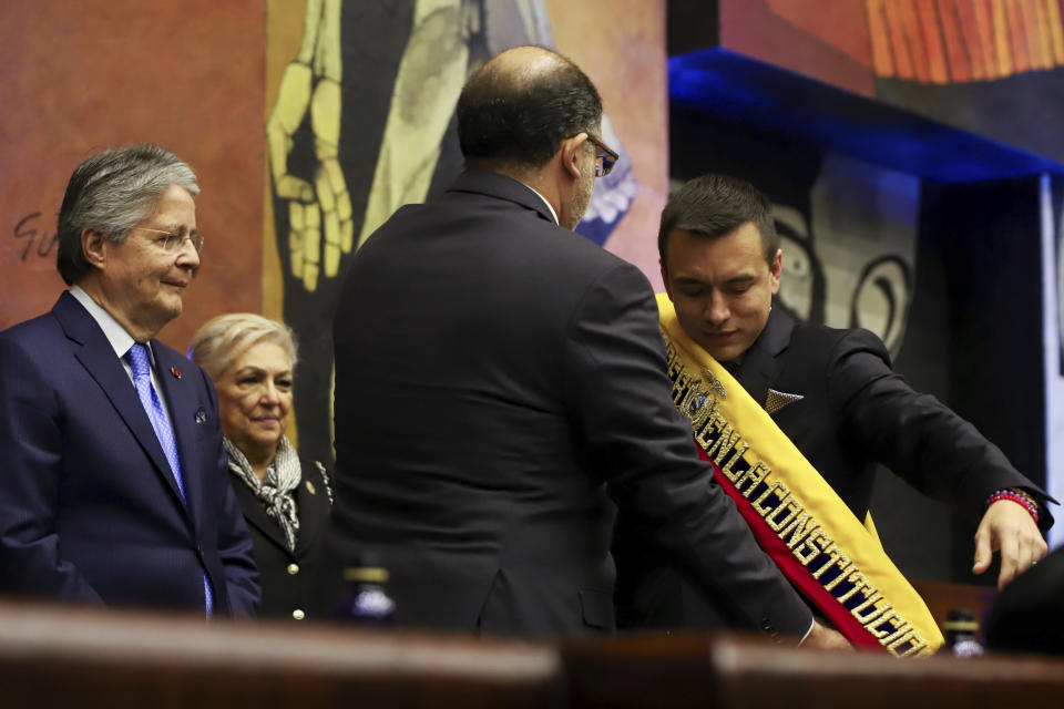National Assembly President Henry Kronfle places the presidential sash on Daniel Noboa after he was sworn-in as the country's new president, during his inauguration ceremony at the National Assembly, in Quito, Ecuador, Thursday, Nov. 23, 2023. At left stands outgoing President Guillermo Lasso. (AP Photo/Juan Diego Montenegro)