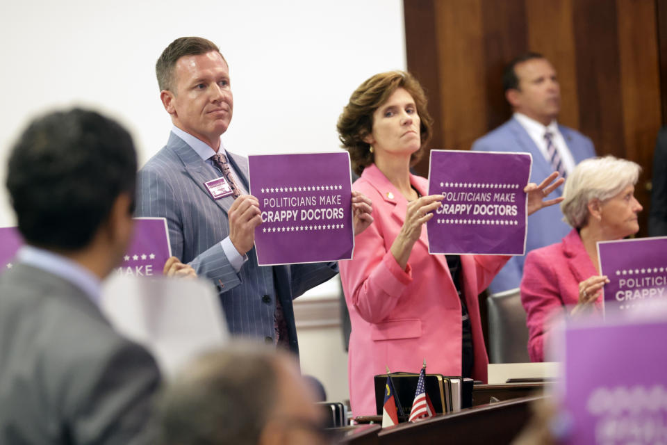Democratic Sens. Michael Garrett, holding sign at left, and Natasha R. Marcus, and other Democrats hold signs in protest, Tuesday, May 16, 2023, in Raleigh, N.C., after the state Senate voted to override Democratic Gov. Roy Cooper's veto of a bill that would change the state's ban on nearly all abortions from those after 20 weeks of pregnancy to those after 12 weeks of pregnancy. Both the Senate and House had to complete successful override votes for the measure to be enacted into law. (AP Photo/Chris Seward)
