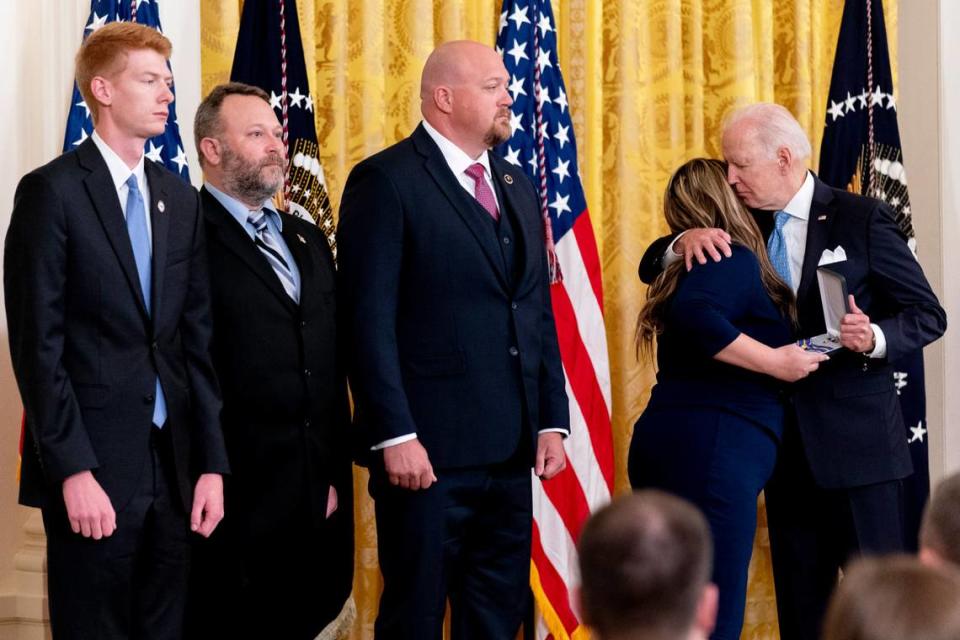 From left, Concord, N.C., Police Officers Kaleb Robinson, Paul Stackenwalt, and Kyle Baker, watch as Haylee Shuping, the wife of fallen Officer Jason Shuping, hugs President Joe Biden. The president awarded the four officers the Public Safety Officer Medal of Valor for their heroism during a gunfight with a carjacking suspect in December 2020.