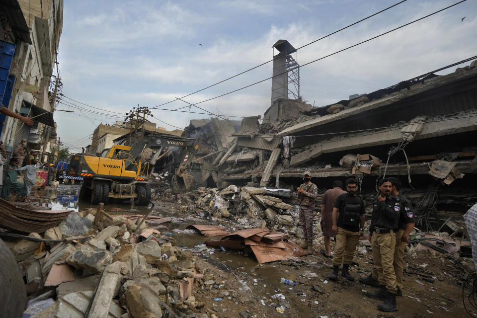 Paramilitary soldier and police officers gather at the site of a fire in Karachi, Pakistan, Thursday, April 13, 2023. A massive fire broke out in a garment factory in the southern Pakistan port city of Karachi. The cause of the blaze, which ripped through the factory Wednesday night and eventually caused it to collapse, was not immediately known, rescue officials and police said. (AP Photo/Fareed Khan)