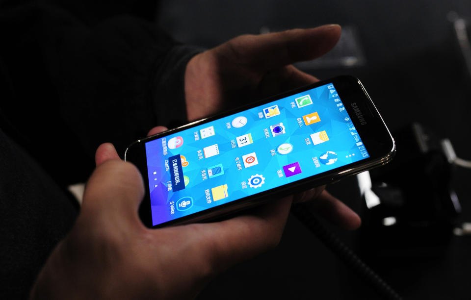 The new Samsung Galaxy S5 is examined by a visitor to the Mobile World Congress, the world's largest mobile phone trade show in Barcelona, Spain, Monday, Feb. 24, 2014, after its unveiling. (AP Photo/Manu Fernandez)