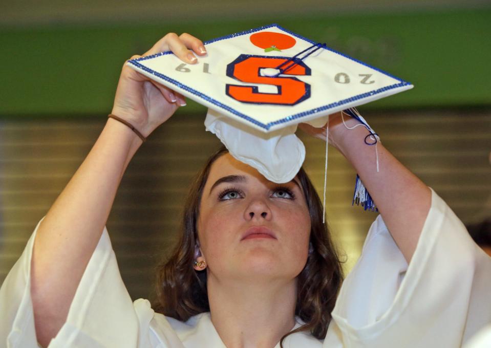 A student heading to Syracuse University in the fall puts on her graduation cap back in June 20, 2015.
