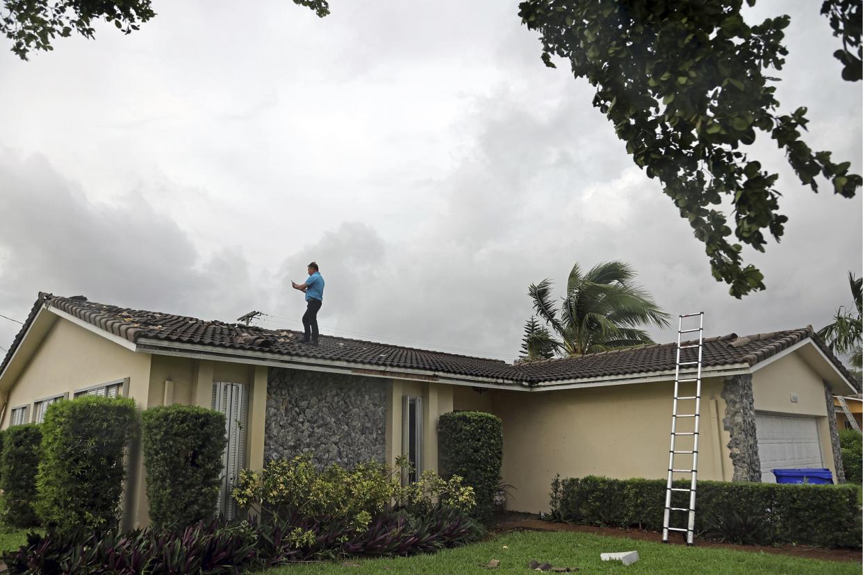 Claudio Szmuc takes pictures atop a roof stripped of its tiles in Hollywood, Fla. on Wednesday, Sept. 28, 2022.