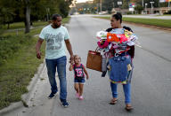 Jose Perez-Santiago, left, and Rosemary Acevedo-Gonzalez, walk with their daughter Jordalis, 2, after retrieving her clothing upon returning to their home for the first time since it was flooded in the aftermath of Hurricane Florence in Spring Lake, N.C., Wednesday, Sept. 19, 2018. "I didn't realize we would lose everything," said Perez-Santiago. "We'll just have to start from the bottom again." (AP Photo/David Goldman)