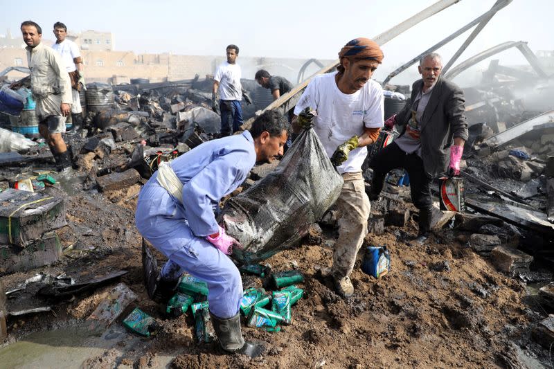 FILE PHOTO: Workers salvage a sack containing oil canisters from the wreckage of a vehicle oil and tires store hit by Saudi-led air strikes in Sanaa