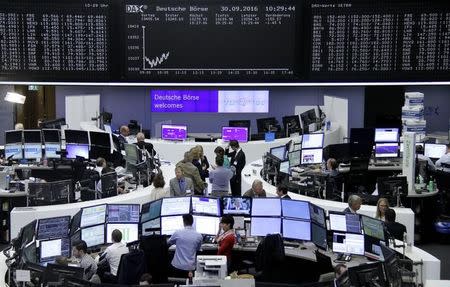 Traders work at their desks in front of the German share price index, DAX board, at the stock exchange in Frankfurt, Germany, September 30, 2016. REUTERS/Staff/Remote