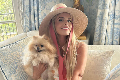 Madison smiling while wearing a sun hat and holding a pomeranian dog.