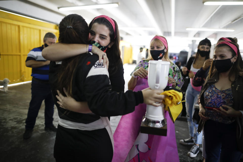 Vitarti Girl’s Team driver Rocio Migliore, back to camera, arrives at pits and is embraced by friends to celebrate her second-place finish at the Oscar y Juan Galvez track in Buenos Aires, Argentina, Sunday, April 4, 2021. The racing team exclusive to females took part in the Top Race Junior series, a national competition, in Argentina for the first time. (AP Photo/Natacha Pisarenko)