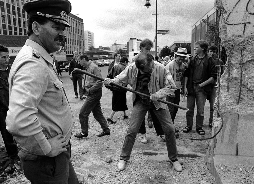 An East German border soldier looks at a man hammering a section of the Berlin Wall near the Allied checkpoint Charlie on June 2, 1990. (Photo: Fabrizio Bensch/Reuters)