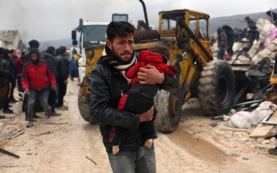 A man carries the body of an earthquake victim in the Besnia village near the Turkish border, Idlib province, Syria - AP