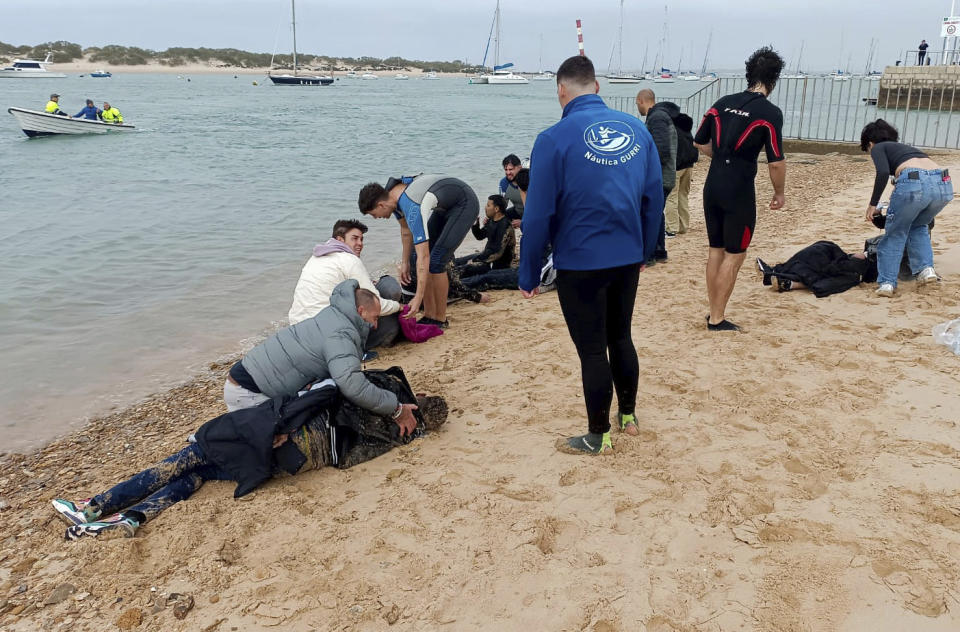 Migrants are rescued by locals on the shore of a beach, close to the southwestern city of Cádiz, Spain, Thursday, Nov. 30, 2023. Four migrants have died meters (yards) from shore in southern Spain after being forced out of the boat they were traveling in, officials said Thursday. The Spanish government press office in the southern province of Cádiz said 31 other people from the boat, including six children, survived the Wednesday afternoon incident and four were taken to a hospital. (AP Photo/Jorge Gonzalez Casares)