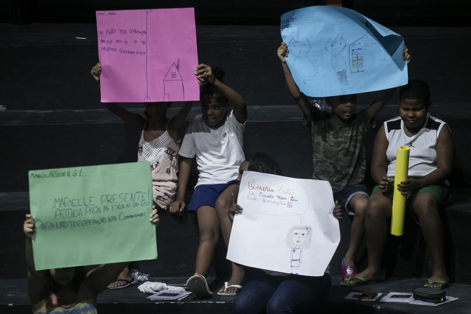 Children hold drawings that represent their experiences of living in the Mare favela during the launch of the book titled “I was supposed to be at school” in the Mare favela of Rio de Janeiro, Brazil, Monday, March 25, 2024. Dozens of kids and teenagers from one of Rio de Janeiro's most violent favelas gathered on Monday to celebrate their most important piece of work yet: a book that aims to show authorities how they see police violence in their Maré community from a young age. (AP Photo/Bruna Prado)