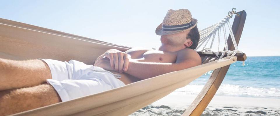 Handsome man resting in the hammock at the beach