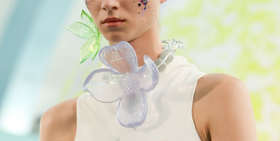 a model wears gigantic floral jewelry at a runway show