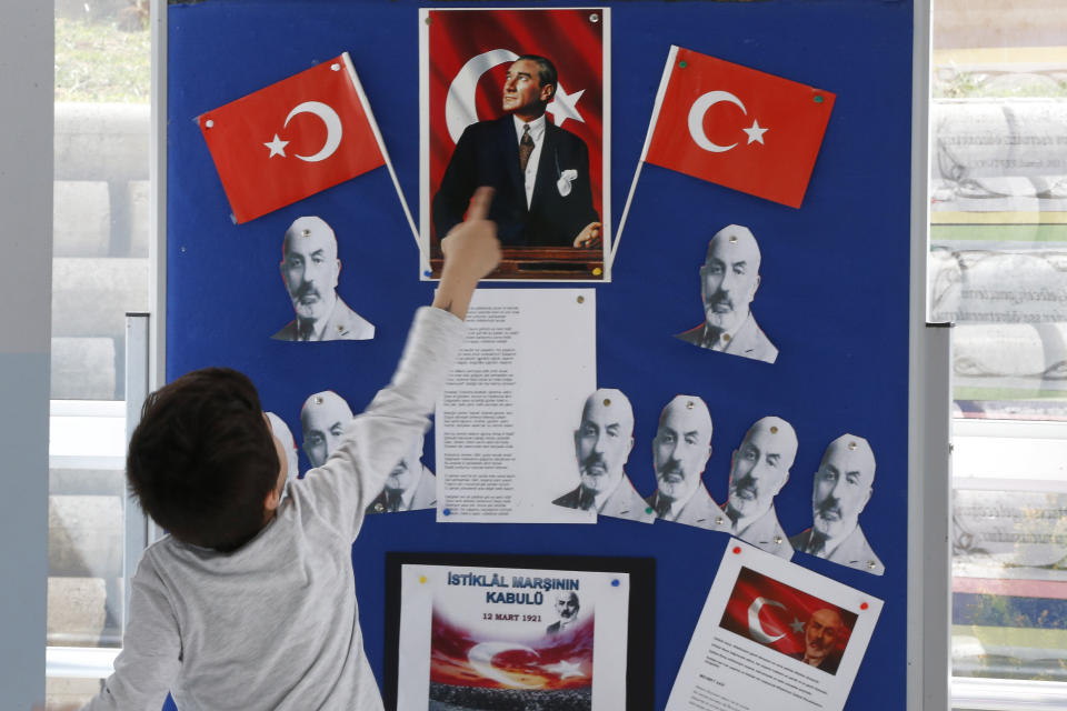 A boy shows the Turkish Republic founder Mustafa Kemal Ataturk portrait on a board school at a polling station during the local elections, in Istanbul, Sunday, March 31, 2019. Turkish citizens have begun casting votes in municipal elections for mayors, local assembly representatives and neighbourhood or village administrators that are seen as a barometer of Erdogan's popularity amid a sharp economic downturn.(AP Photo/Lefteris Pitarakis)