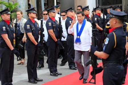 President Rodrigo Duterte salutes while passing members of custom police, upon arrival to witness the destruction of condemned smuggled luxury cars worth 61,626,000.00 pesos (approximately US.2 million), which include used Lexus, BMW, Mercedes-Benz, Audi, Jaguar and Corvette Stingray, during the 116th Bureau of Customs founding anniversary in Metro Manila, Philippines February 6, 2018. REUTERS/Romeo Ranoco