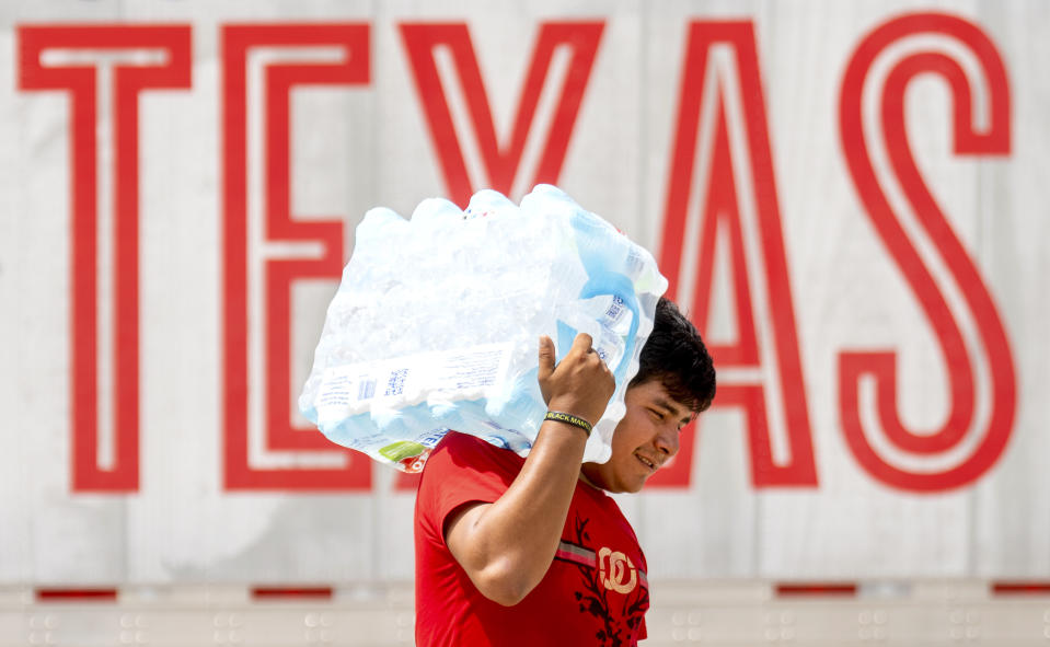 A man carries water on his shoulder as volunteers at the Memorial Assistance Ministries distributed water and ice, Saturday, May 18, 2024, in Houston. As of Saturday afternoon, 486,000 people in the Houston area remained without power after a Thursday's thunderstorms killed at least seven people. (Jason Fochtman/Houston Chronicle via AP)