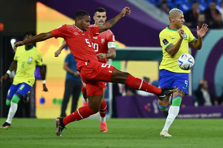 El defensor suizo Manuel Akanji despeja la pelota ante la presión de Richarlison, durante el partido entre Brazil y Suiza