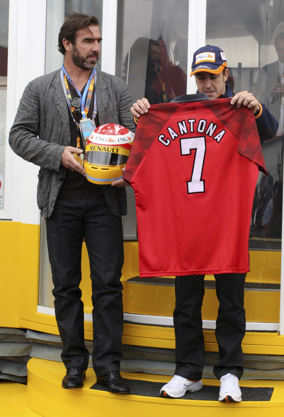 Former Manchester United player Eric Cantona of France poses with Renault driver Fernando Alonso of Spain having exchanged gifts prior to the start of the British Formula One Grand Prix at the Silverstone racetrack, in Silverstone, England, Sunday, June 21 2009. (AP Photo/Tom Hevezi)