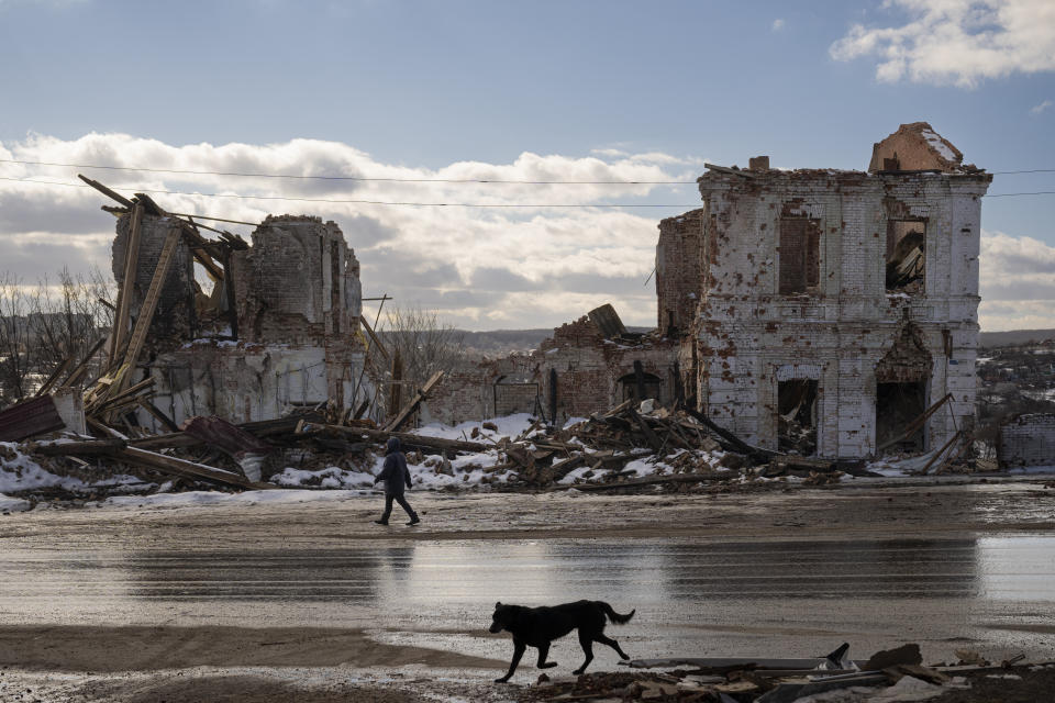 FILE - A woman walks by a building destroyed by a Russian strike in Kupiansk, Ukraine, Monday, Feb. 20, 2023. An international arrest warrant for President Vladimir Putin raises the prospect of justice for the man whose country invaded Ukraine but complicates efforts to end that war in peace talks. (AP Photo/Vadim Ghirda, File)