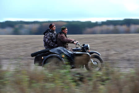 Vladimir Krivenchik (R) and Nikolay Skidan, hunters, ride a motorcycle near the village of Khrapkovo, Belarus November 4, 2016. REUTERS/Vasily Fedosenko