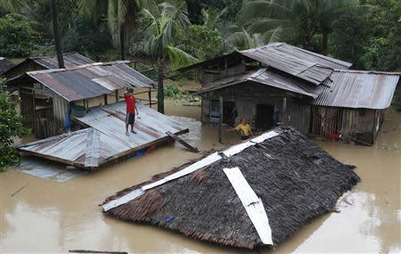 A resident stands on the roof of his home that is submerged in heavy flooding brought by tropical depression "Agaton", in Butuan city on the southern Philippine island of Mindanao January 21, 2014. REUTERS/Erik De Castro