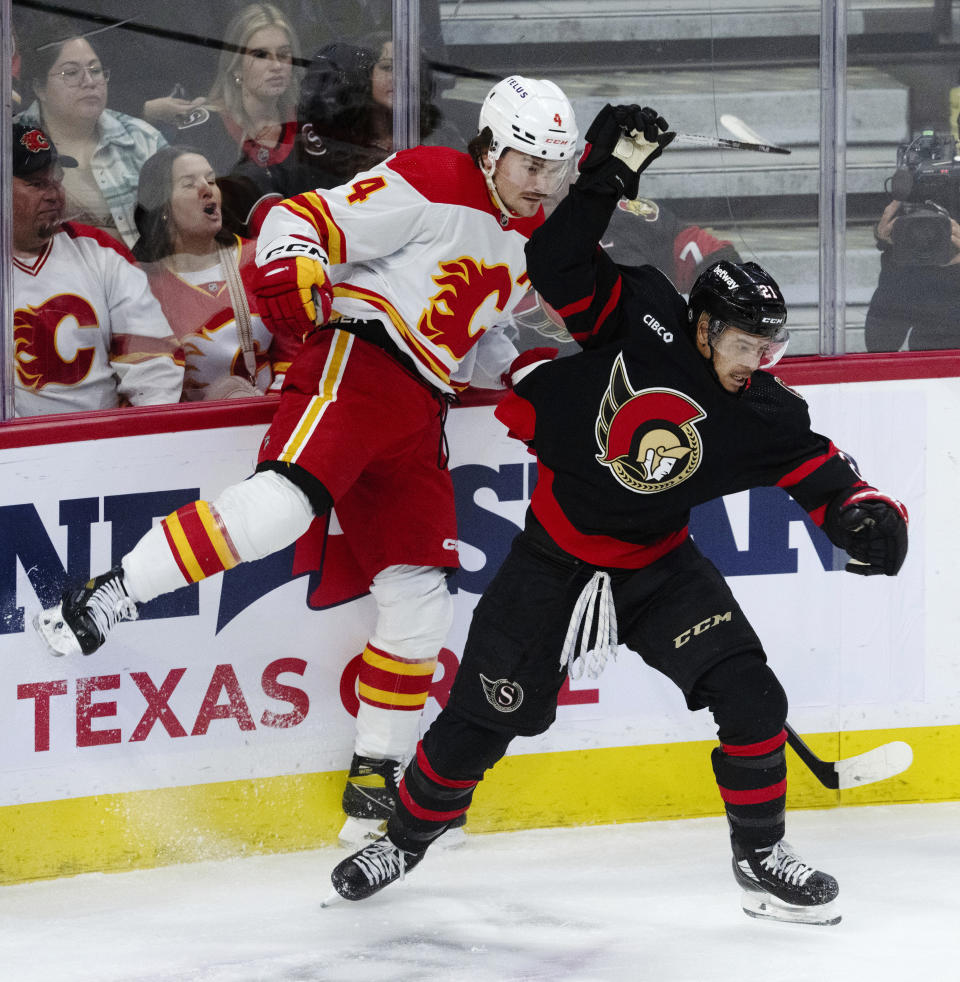 Ottawa Senators right wing Mathieu Joseph collides with Calgary Flames defenseman Rasmus Andersson along the boards during the first period of an NHL hockey game, Saturday, Nov. 11, 2023 in Ottawa, Ontario. (Adrian Wyld/The Canadian Press via AP)