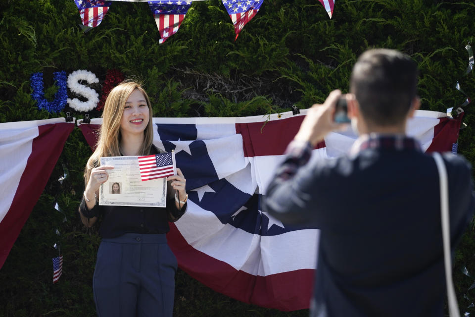 In this June 26, 2020 photo, Sherry Nhi Nguyen has her photo taken by James Tran after she was sworn in as a U.S. citizen during a drive-up naturalization ceremony in Laguna Niguel, Calif. Nguyen was previously a citizen of Vietnam. U.S. Citizenship and Immigration Services held the ceremony after in-person services were temporarily suspended due to the spread of COVID-19. The U.S. has resumed swearing in new citizens but the oath ceremonies aren't the same because of COVID-19 and a budget crisis at the citizenship agency threatens to stall them again. (AP Photo/Ashley Landis)