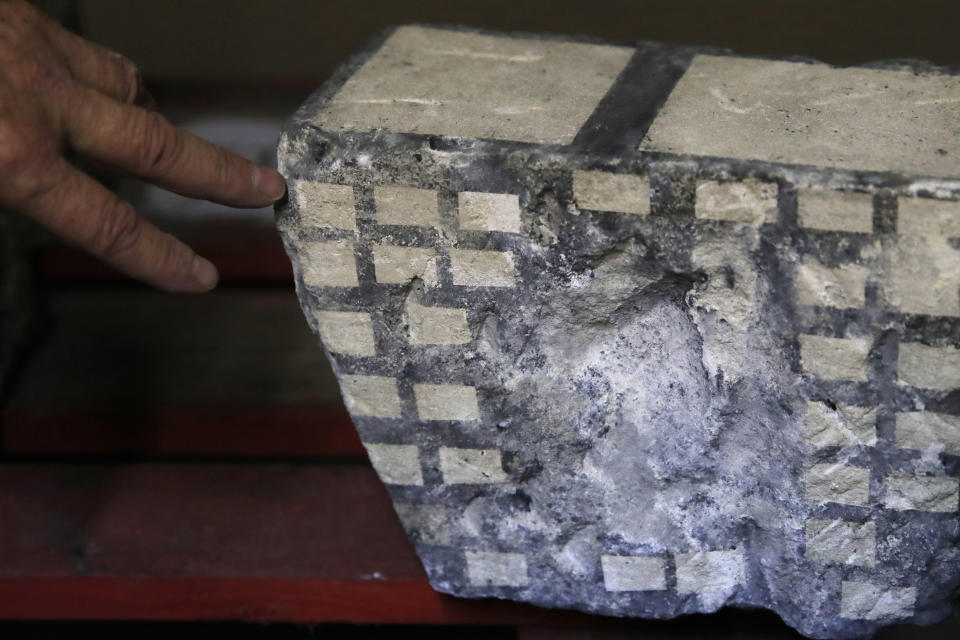 In this photo taken on Wednesday, Oct. 9, 2019, stone expert Jean-Didier Mertz shows the tests of laser cleaning technique on a broken vault stone from Notre Dame cathedral in a warehouse at Champs-sur-Marne, west of Paris. Scientists at the French government's Historical Monuments Research Laboratory are using these objects as clues in an urgent and vital task, working out how to safely restore the beloved Paris cathedral and identify what perils remain inside in a race against the clock. (AP Photo/Francois Mori)