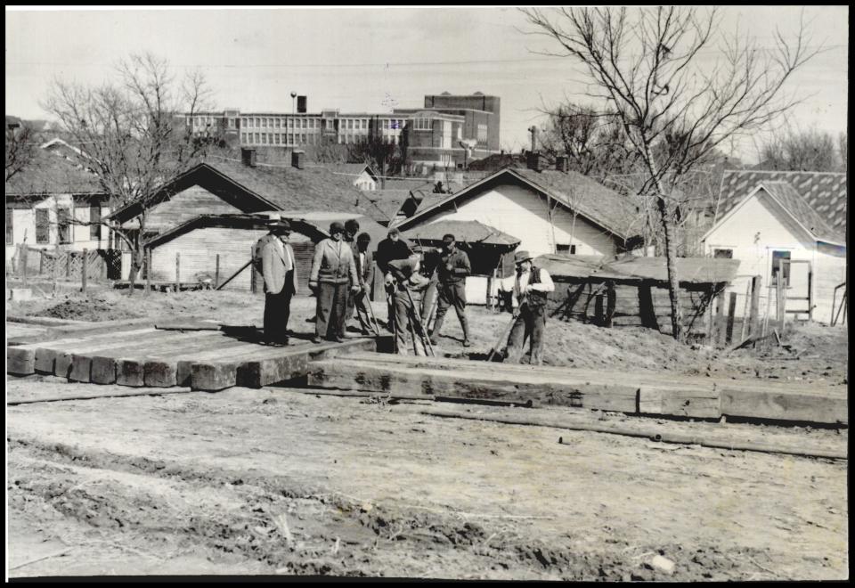 The former Douglass High School/Page Woodson School can be seen in the foreground as crews prepare to drill an oil well next to homes in the John F. Kennedy neighborhood. Black Oklahoma City residents were restricted to living in the area east of downtown and industrial use, including scrap yards and refineries were allowed to operate in and around the neighborhood for decades.