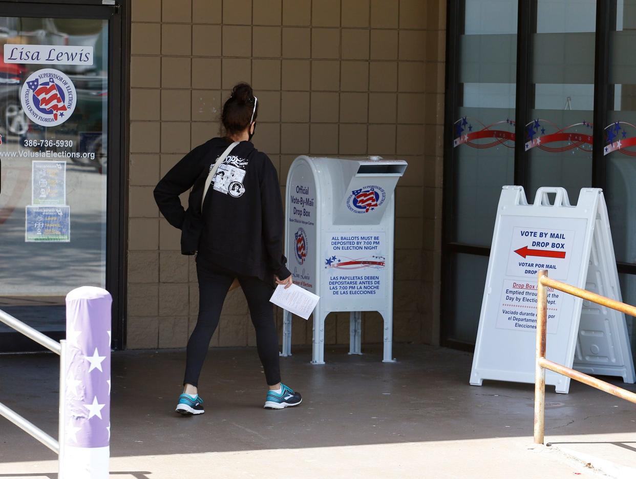 A voter prepares to drop her ballot in the drop box  outside the Supervisor of Elections office in DeLand on the last day of early voting, Saturday, Oct. 31, 2020. 