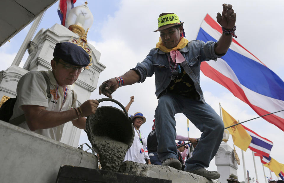 Anti-government protesters pour cement on concrete barriers to seal the gate of the prime minister's office of government house during a rally in Bangkok, Thailand, Monday, Feb. 17, 2014. Suthep Thaugsuban led hundreds of protesters to surround the government house after hearing that Prime Minister Yingluck Shinawatra will this week return to work at her office. (AP Photo/Wason Wanichakorn)