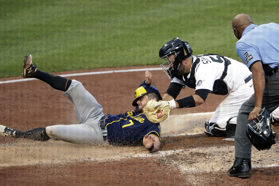 Pittsburgh Pirates catcher Jacob Stallings, center, tags out Milwaukee Brewers' Eric Sogard (7) with umpire C.B. Bucknor making the call during the third inning of a baseball game in Pittsburgh, Wednesday, July 29, 2020. Sogard was attempting to score on a single by Keston Hiura to left field. (AP Photo/Gene J. Puskar)